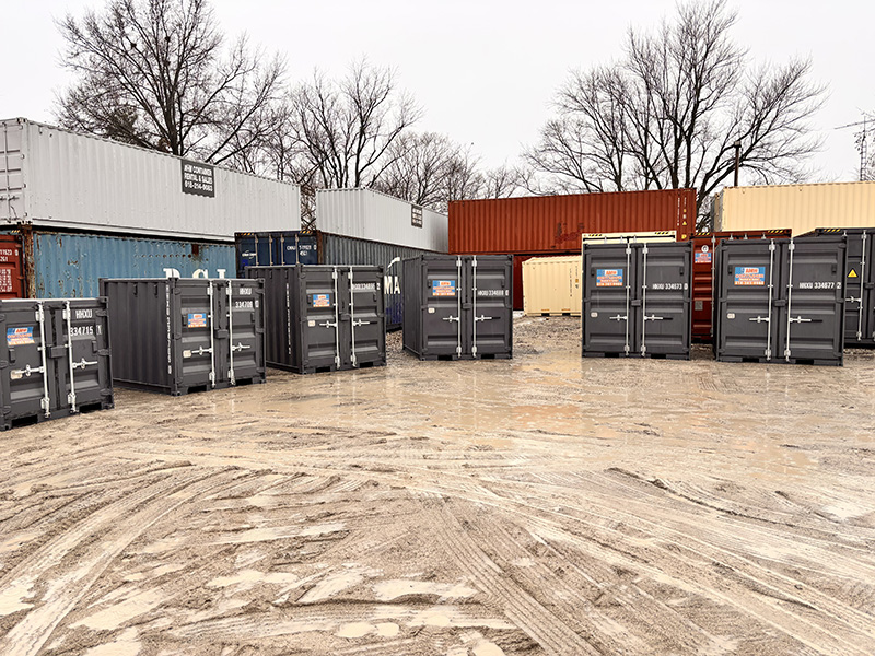 Row of gray 10-ft shipping containers lined up in front of larger stacked containers for sale in Garyville, IL. 
