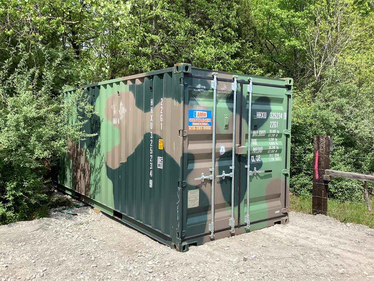 Camouflage 20 foot shipping container placed on a gravel pad for long-term storage at a rural property.<br />
