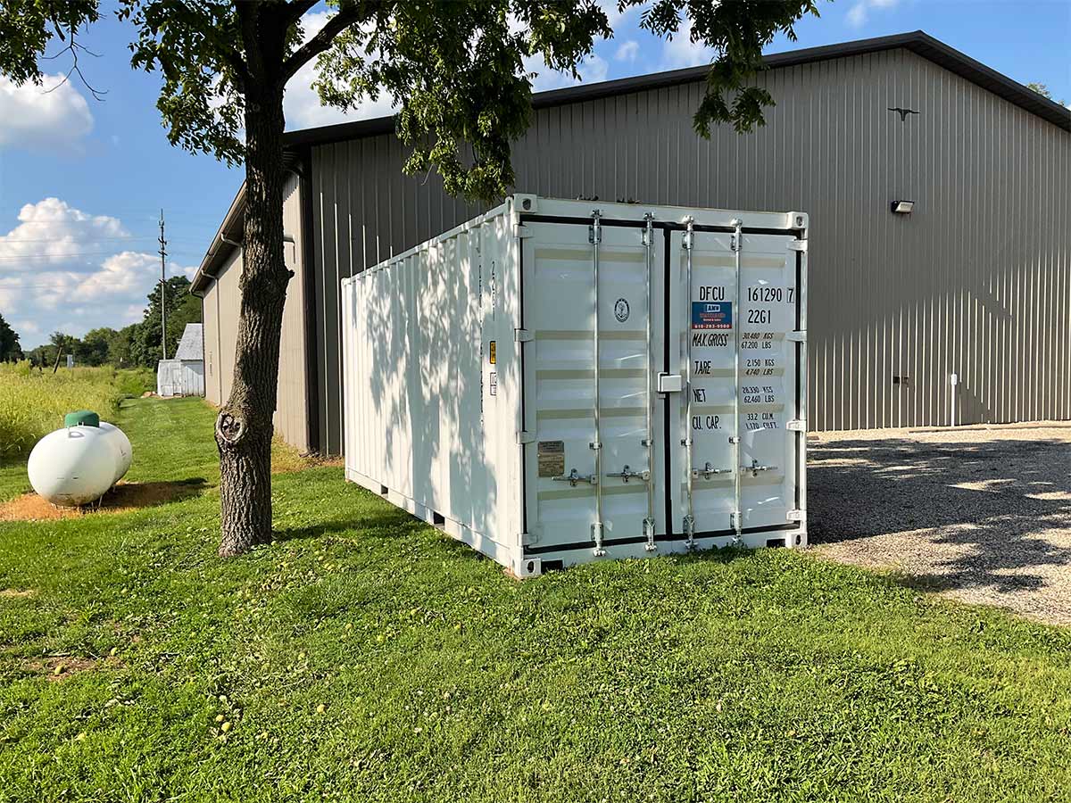 White 20 foot container beside a commercial building providing convenient on-site long-term storage.