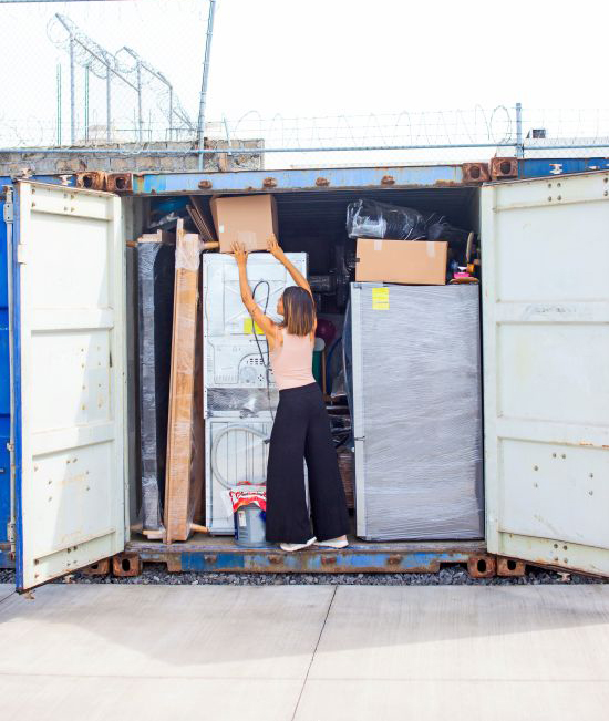 Woman organizing boxes, furniture and appliances inside a shipping container for long-term storage.